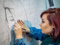 Student drawing a portrait with pencil on large graph paper on wall at the 艺术学院.