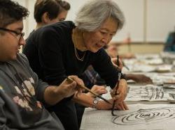 Professor in Calligraphy class drawing spiral on newspaper in front of student at the 人文社会科学学院